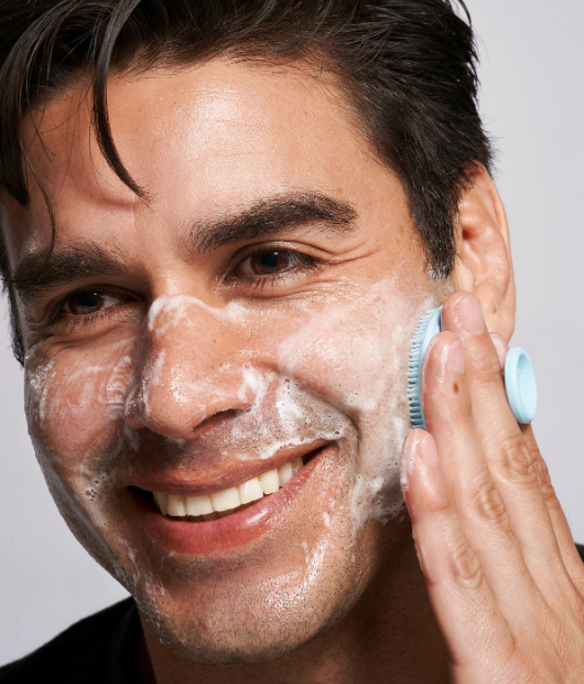 Man smiling using exfoliating scrubber