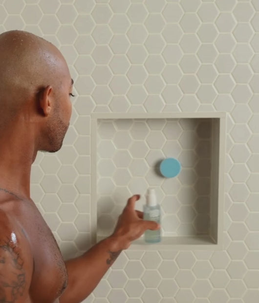 Man using gel cleanser and exfoliating brush in shower
