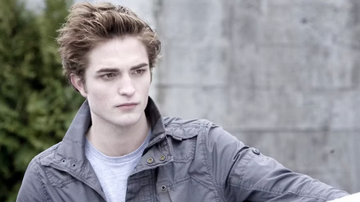 Young man with light skin and styled hair wearing a gray jacket outdoors