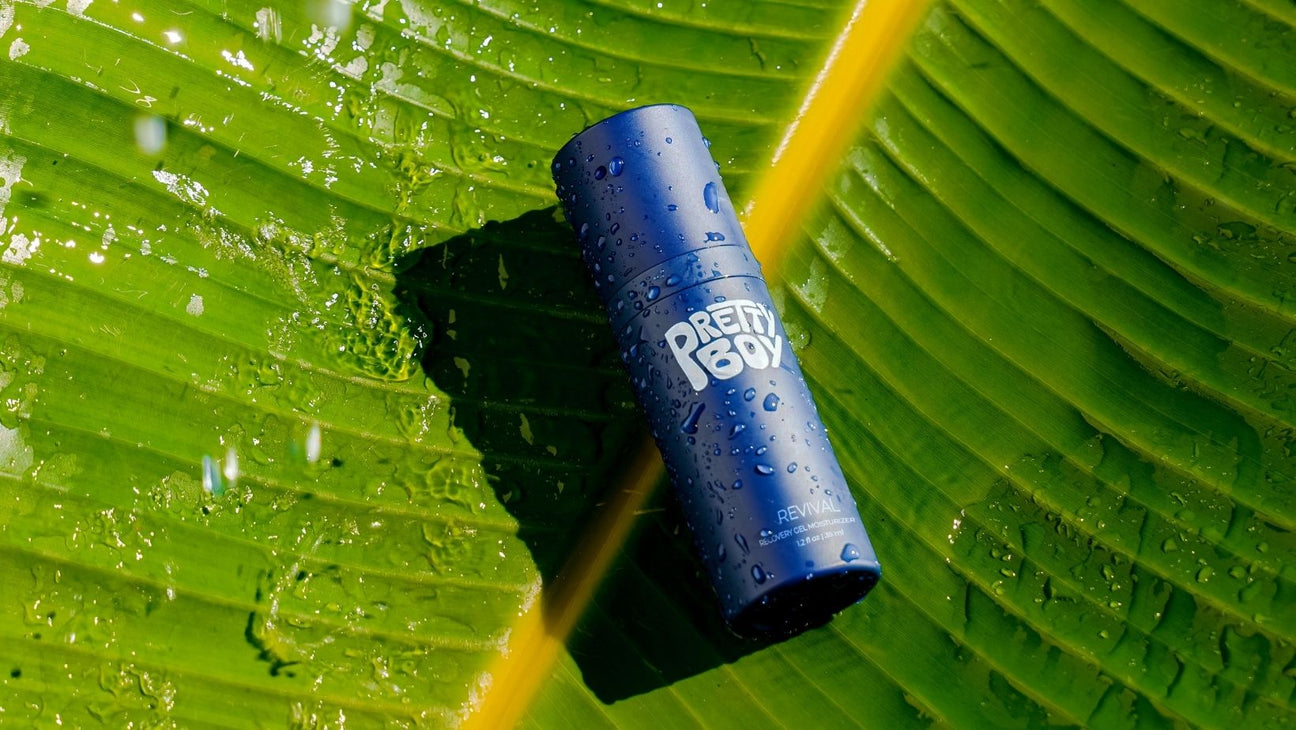 Blue Pretty Boy Revwal Recovery Gel Moisturizer bottle with water droplets on a green leaf