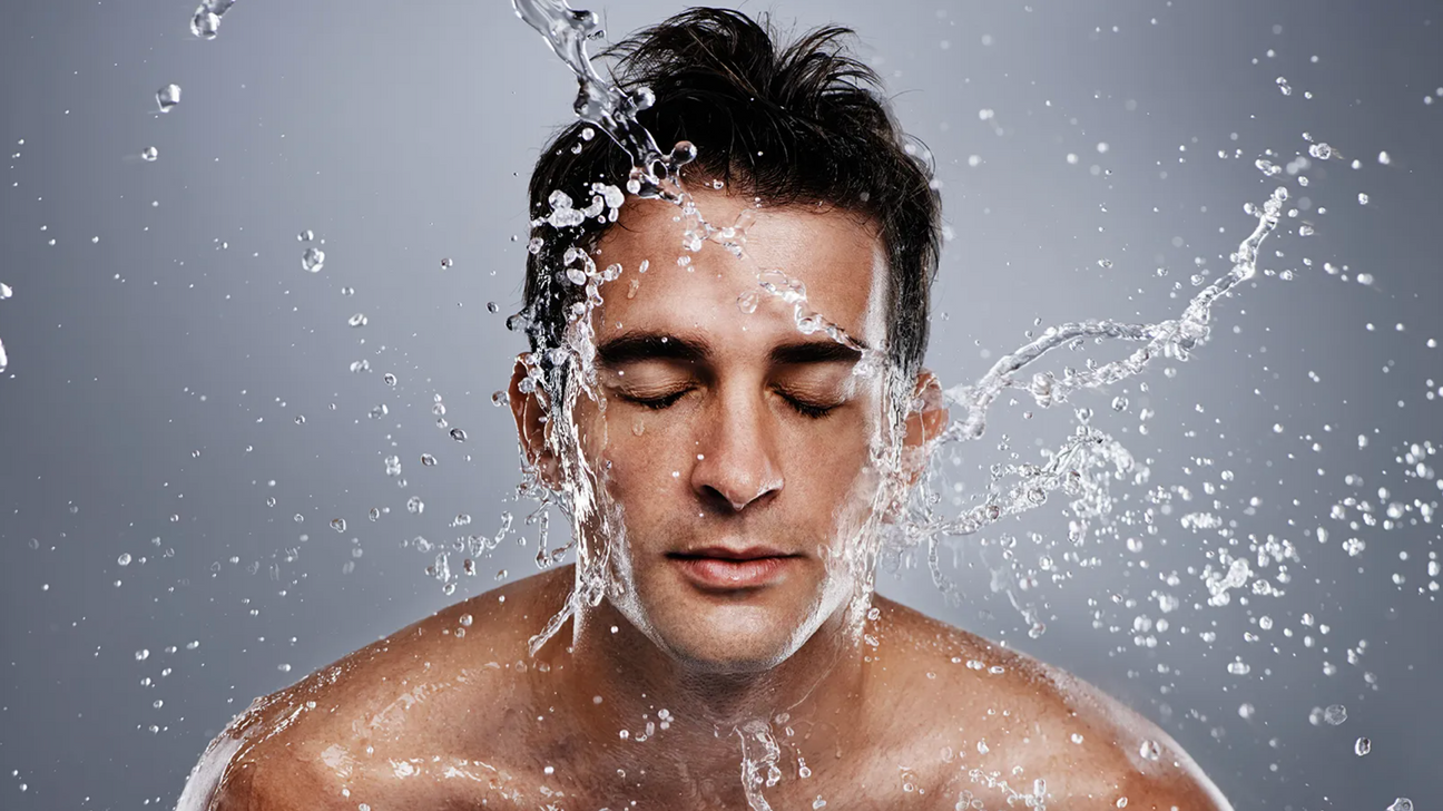 Man splashing water on his face with eyes closed, illustrating skincare routine for men