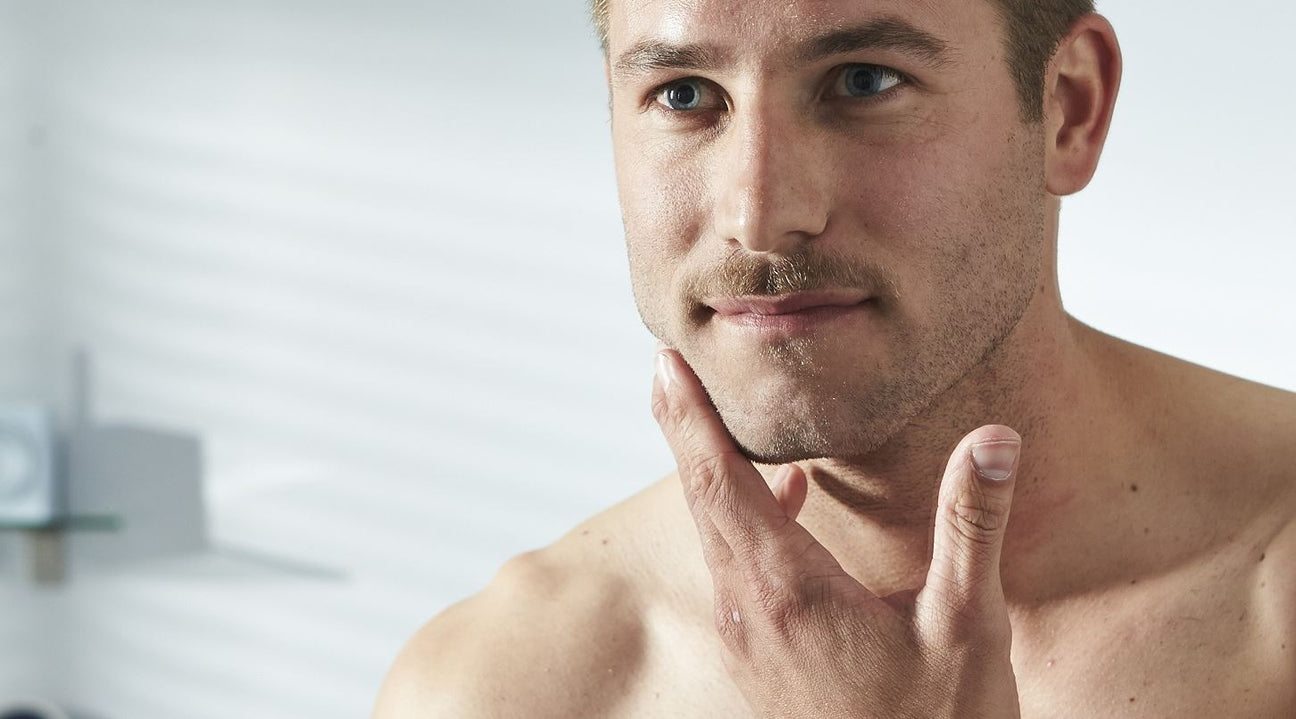 Man touching his chin and cheek, considering skincare routine