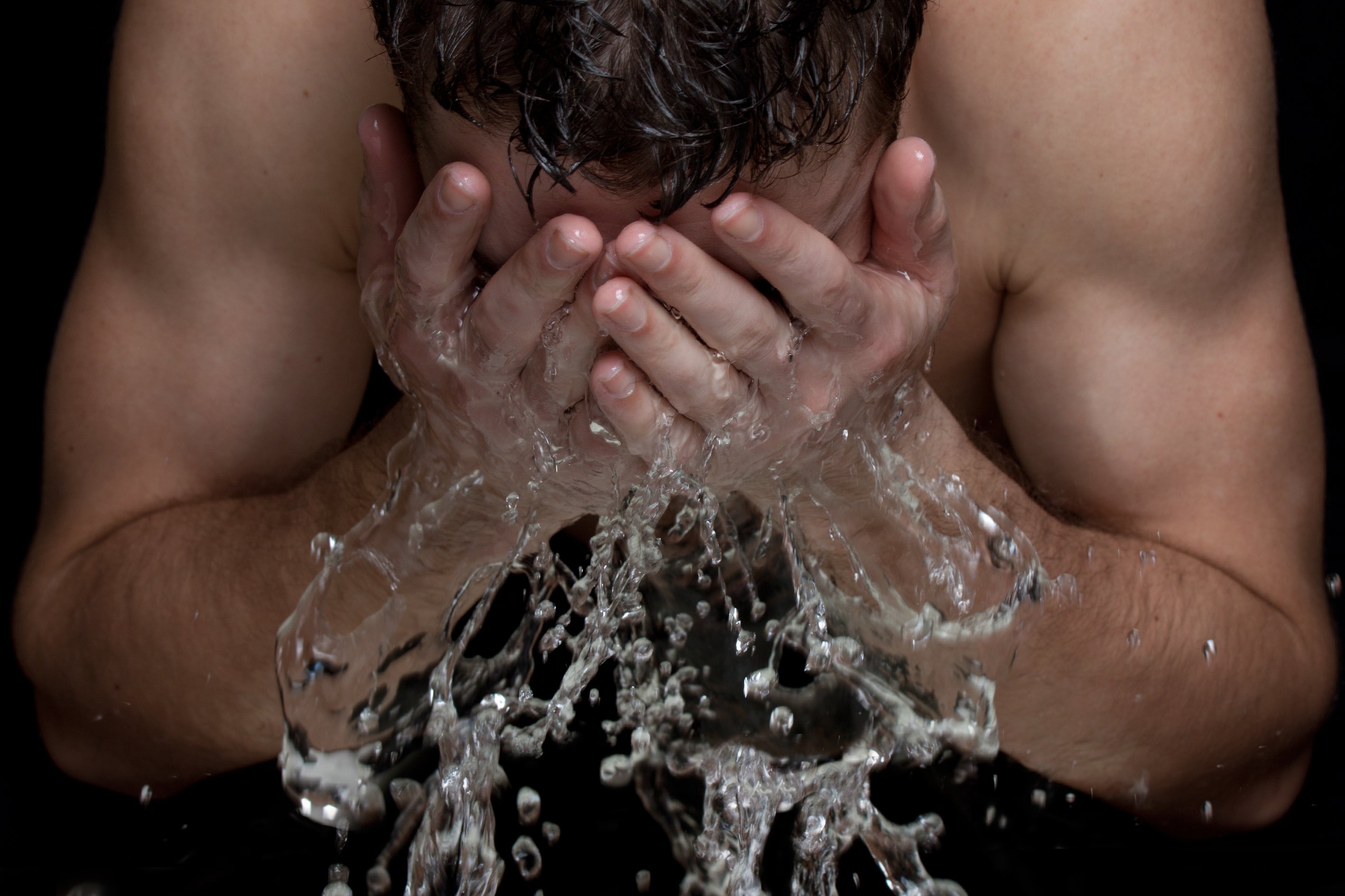 Man splashing water on his face as part of a skincare routine