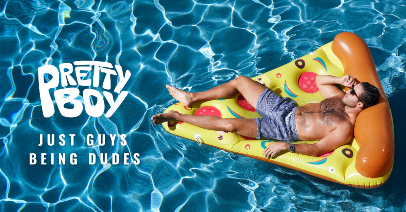 Man wearing sunglasses and swim trunks lounging on a pizza-shaped float in a pool with text: PRETTY BOY JUST GUYS BEING DUDES