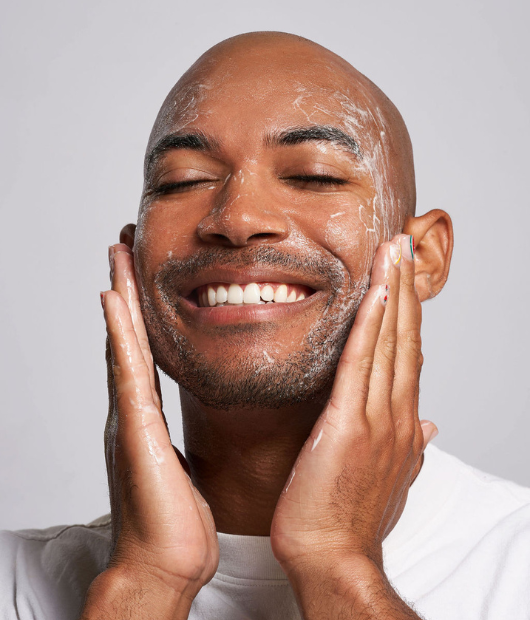 Man smiling using cleanser on face
