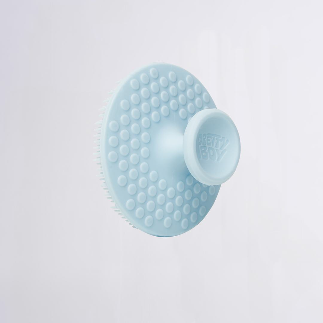 Silicone round scalp brush with circular nubs and central knob stamped 'PRETTY BOY'.